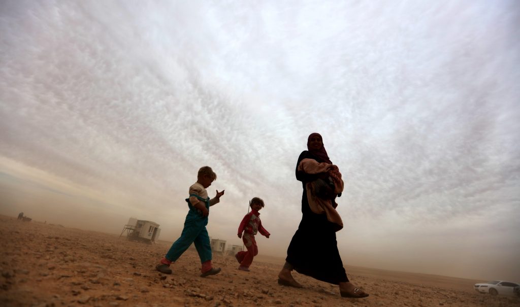 Syrian refugees walk to a camp at the Jordanian side of the Jordan-Syria border near Royashed Town in Jordan
