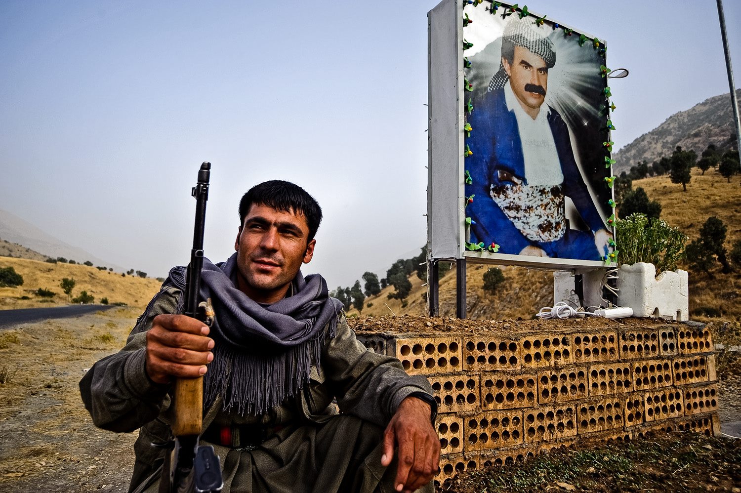 Un combattente curdo davanti a un'immagine di Ocalan (LaPresse)