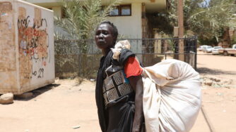 A Sudanese woman carries her belongings on a street in Khartoum, Sudan